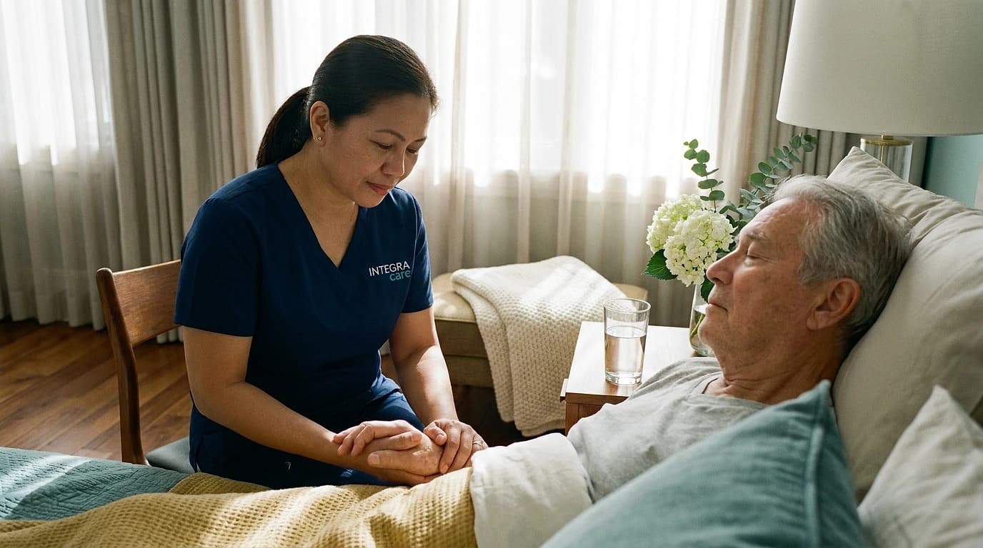 A caregiver gently holds the hand of a senior recovering from a stroke as he rests peacefully in a sunlit, well-appointed bedroom at home.